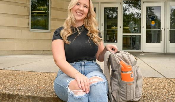 A woman sits on some steps in front of a building on ODU's campus. 